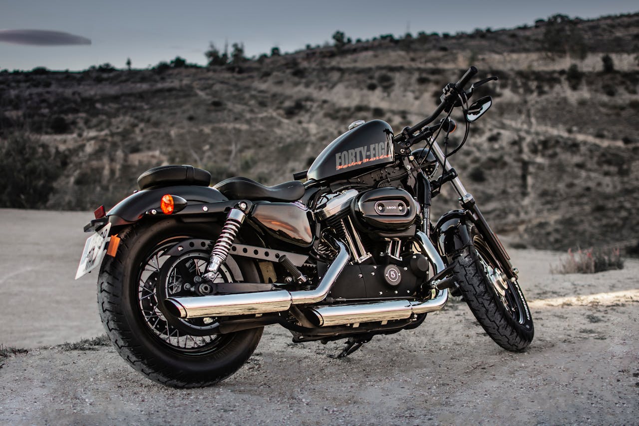 A parked Harley Davidson motorcycle on a gravel path with a scenic background, exuding freedom and adventure.